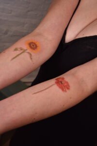 Micro color realism autumn maple leaf tattoo in orange and yellow on inner arm