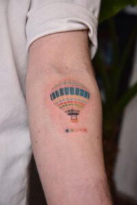 Colorful pointillism hot air balloon tattoo on inner arm at Names Tattoo Studio in Lisbon