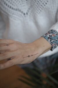 Black linework handpoke water lily tattoo on the wrist