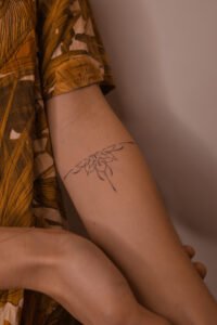 Micro color realism Monstera leaf tattoo with green and red variegation on inner forearm