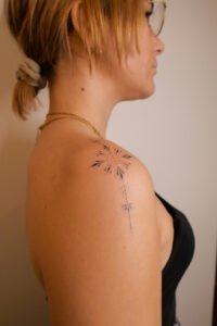 Minimalist geometric sun tattoo with fine line detail on the shoulder