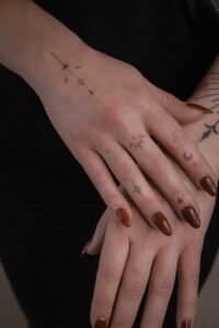 Fine line celestial hand tattoo featuring stars, crescent moon, and dainty dots