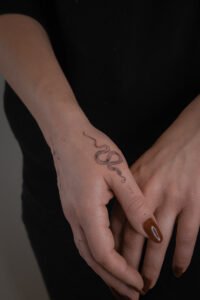 Blue ink ornamental tattoo inspired by azulejo Portuguese tile patterns, featuring a symmetrical diamond-shaped design with intricate fine-line scrolls and floral motifs on the skin