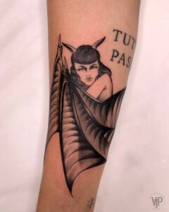 Blue ink ornamental tattoo inspired by azulejo Portuguese tile patterns, featuring a symmetrical diamond-shaped design with intricate fine-line scrolls and floral motifs on the skin