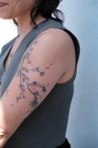 Micro color realism autumn maple leaf tattoo in orange and yellow on inner arm