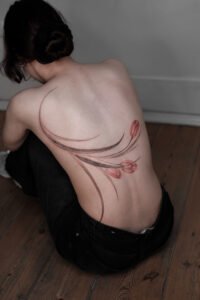 A fine-line Sanskrit script tattoo on the forearm featuring an Om symbol inside a sunburst, a blooming lotus flower, and delicate ornamental swirls, crafted at Names Tattoo Studio in Lisbon