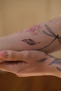 Delicate botanical leaf tattoo with soft dotwork shading on the forearm