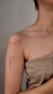 Black linework handpoke water lily tattoo on the wrist