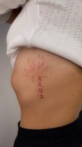 Elegant red flower and Kanji handpoke tattoo on the ribs
