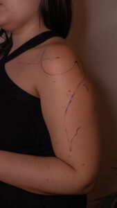 Fine line abstract tattoo flowing from the shoulder down the arm