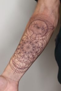 Sacred geometry forearm tattoo in a black ink fine line style, featuring a detailed Flower of Life pattern transitioning into complex overlapping circles