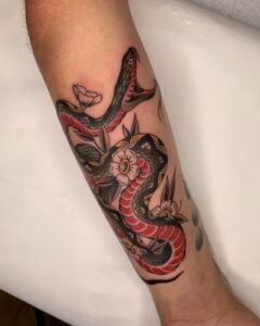 Traditional Japanese tiger tattoo on forearm with bold black shading and red floral accents