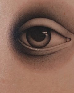 Hyper-realistic eye tattoo with soft black and grey shading and white highlights, realistic human eye peeking through skin on arm