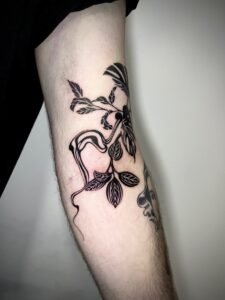 Black linework handpoke water lily tattoo on the wrist