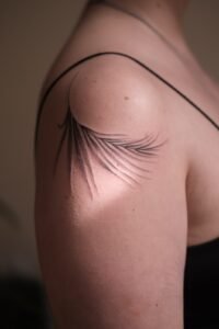 Small fineline skull tattoo with floral mandala detail on thigh