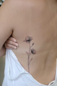 Micro-realism autumn maple leaf tattoo on the inner wrist, featuring a vibrant gradient of green, yellow, orange, and red with delicate stem detail