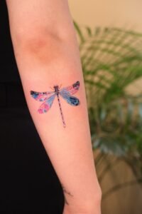 Small fineline skull tattoo with floral mandala detail on thigh