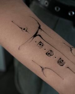 A fine-line Sanskrit script tattoo on the forearm featuring an Om symbol inside a sunburst, a blooming lotus flower, and delicate ornamental swirls, crafted at Names Tattoo Studio in Lisbon