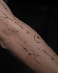 Micro color realism autumn maple leaf tattoo in orange and yellow on inner arm