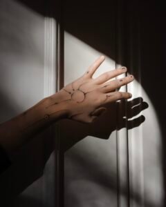 A fine-line Sanskrit script tattoo on the forearm featuring an Om symbol inside a sunburst, a blooming lotus flower, and delicate ornamental swirls, crafted at Names Tattoo Studio in Lisbon