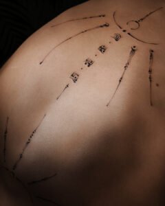 Micro-realism autumn maple leaf tattoo on the inner wrist, featuring a vibrant gradient of green, yellow, orange, and red with delicate stem detail