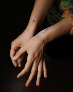 Minimalist fine line abstract symbol tattoos on both wrists of a person, featuring delicate black ink curves and dots in a contemporary style at Names Tattoo Studio in Lisbon