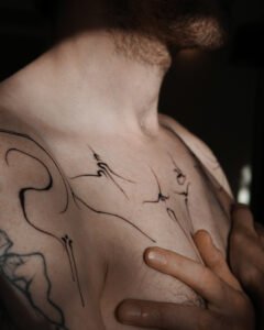 Blue ink ornamental tattoo inspired by azulejo Portuguese tile patterns, featuring a symmetrical diamond-shaped design with intricate fine-line scrolls and floral motifs on the skin