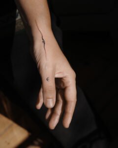 Micro color realism Monstera leaf tattoo with green and red variegation on inner forearm