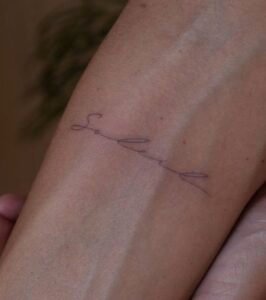 Fine line script tattoo of the name Soleil in cursive on a forearm, featuring elegant thin strokes and minimalist aesthetic, Names Tattoo Studio in Lisbon