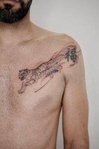 Micro-realism autumn maple leaf tattoo on the inner wrist, featuring a vibrant gradient of green, yellow, orange, and red with delicate stem detail